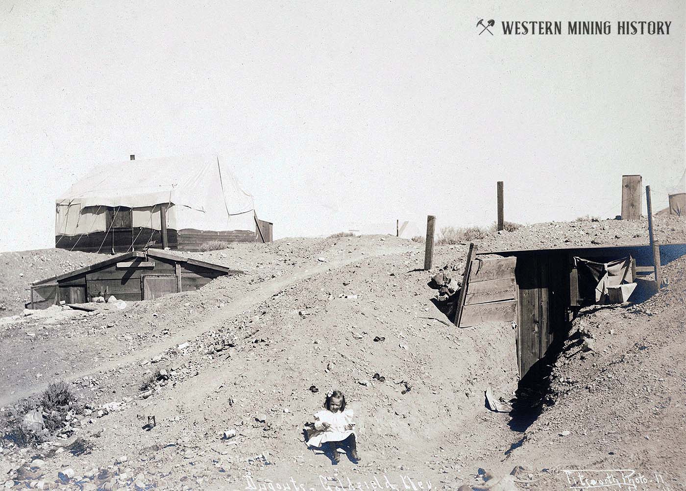 Child sits in front of Dugout cabin in Goldfield, Nevada