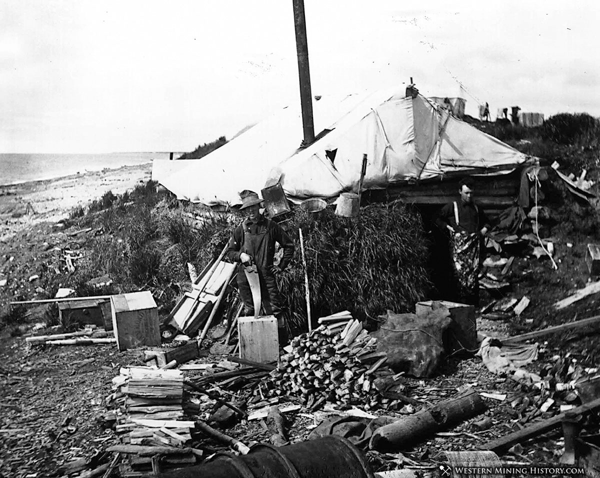 Miners stand by their cabin on a Nome beach ca. 1900