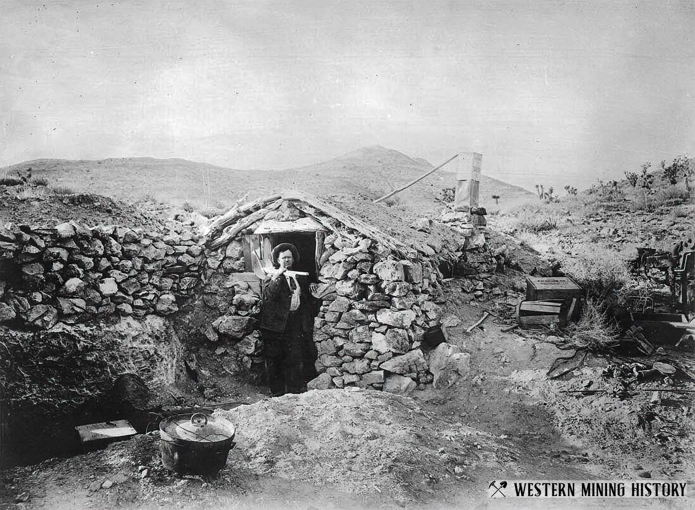 Miner standing next to his home made of rocks - Randsburg